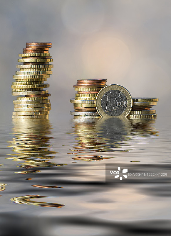 阳光照射并反射在水面上的欧元硬币堆图片素材