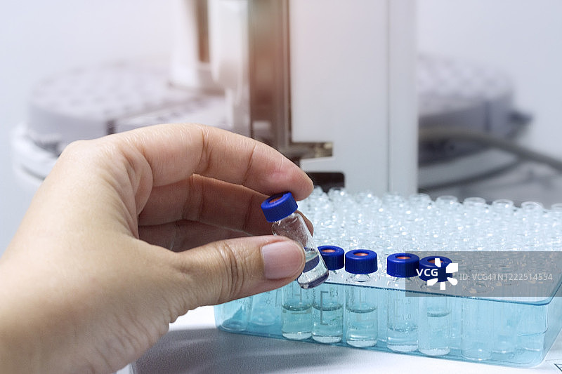 手持样品瓶，准备气相色谱仪测试样品图片素材