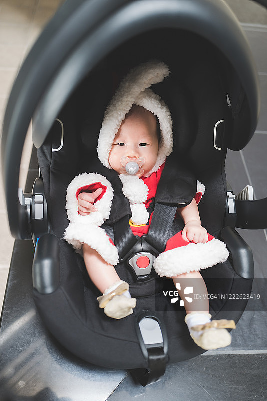 亚洲宝宝穿着圣诞老人服装坐在汽车座椅上图片素材