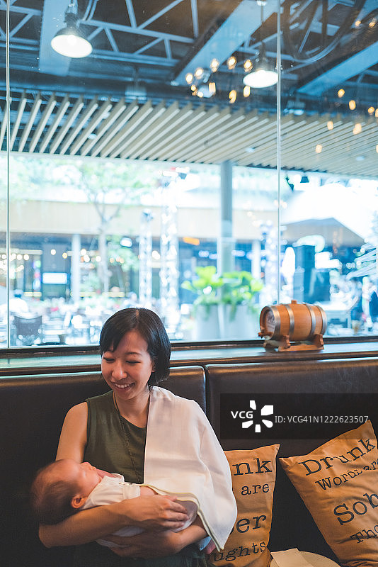 亚洲母亲在餐厅亲切地抱着女儿图片素材