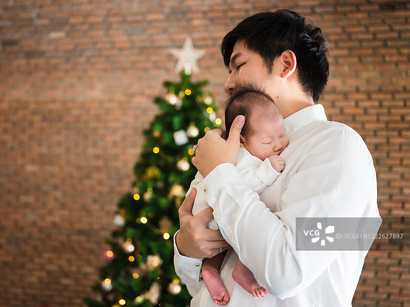 圣诞主题亚洲家庭照，父亲和新生儿，侧面图片素材