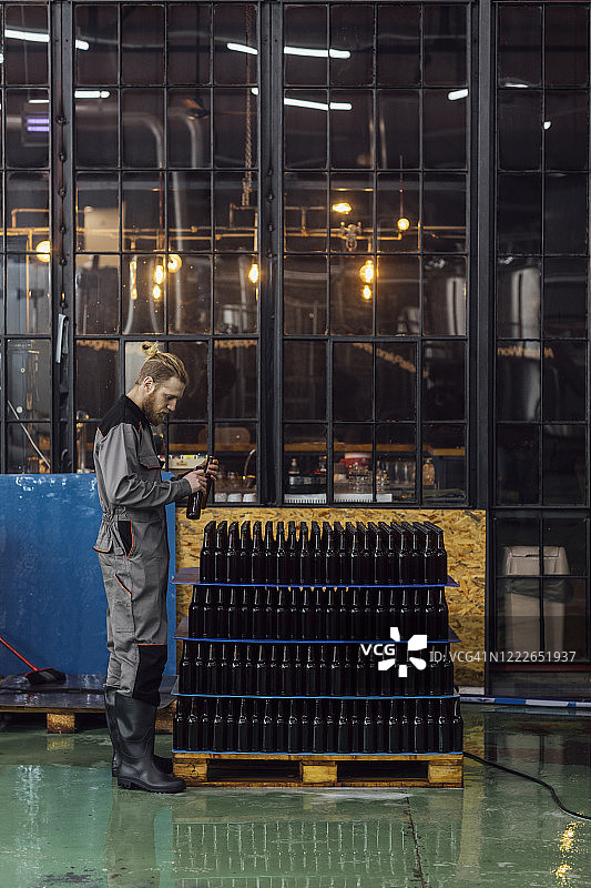 工厂工人检查瓶装啤酒的广角镜头图片素材