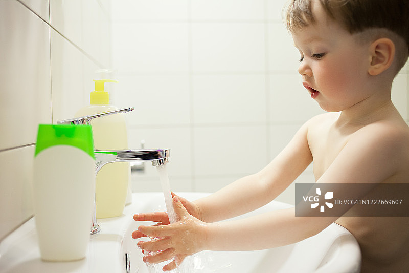 2岁男婴在浴室用肥皂洗手图片素材