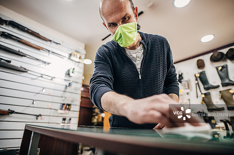 中年男人在开业前对枪店进行消毒图片素材