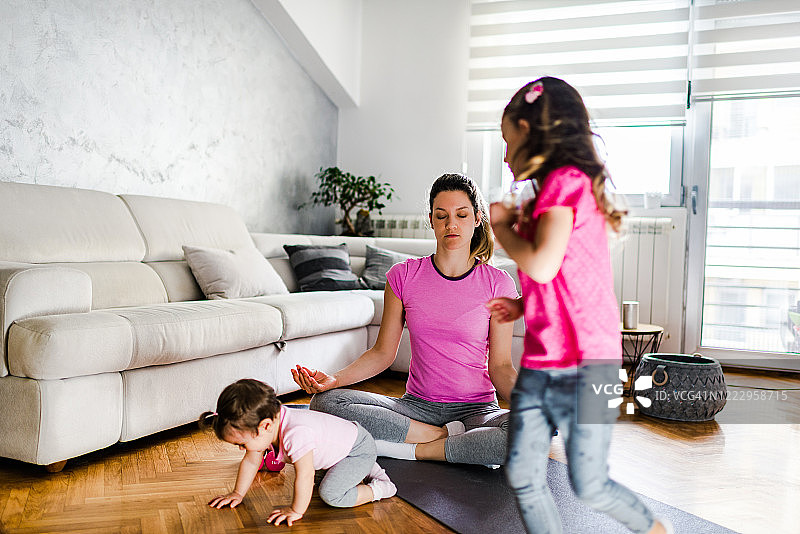 在嘈杂的孩子们奔跑时，年轻的母亲在冥想图片素材