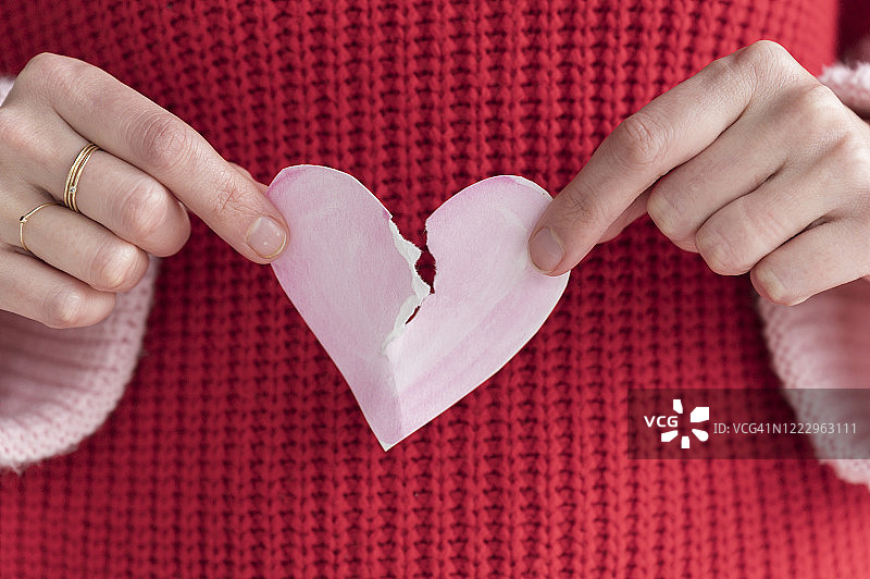 女人将纸质爱心撕成两半图片素材