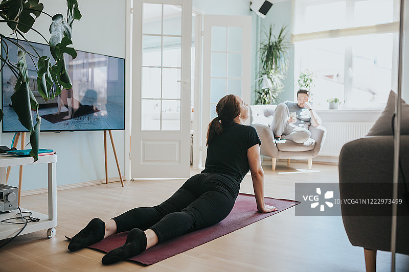 成年女性在线上瑜伽课中做向上犬式图片素材