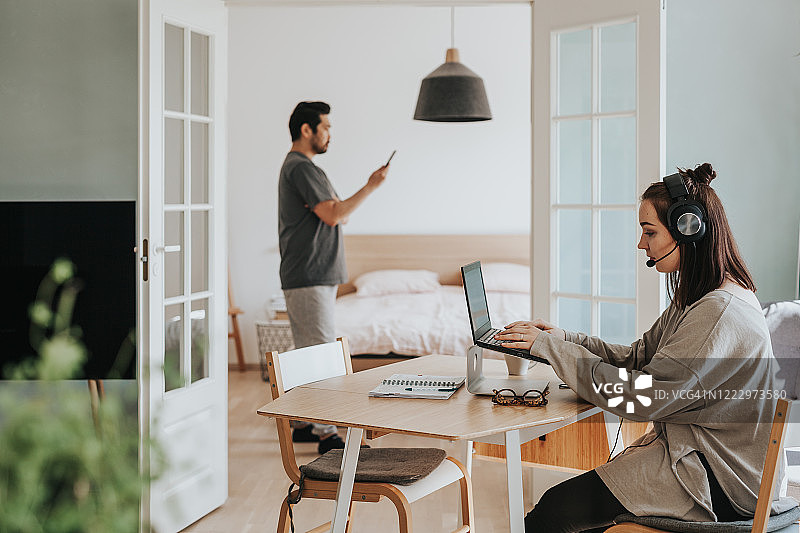 中年妇女在家办公，丈夫在阅读电子书图片素材