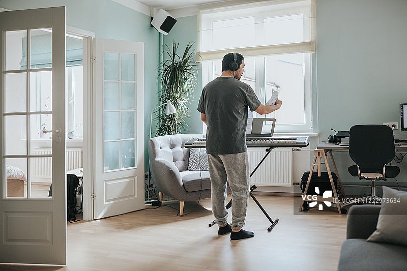 星期天早上在家玩合成器的日本男人图片素材