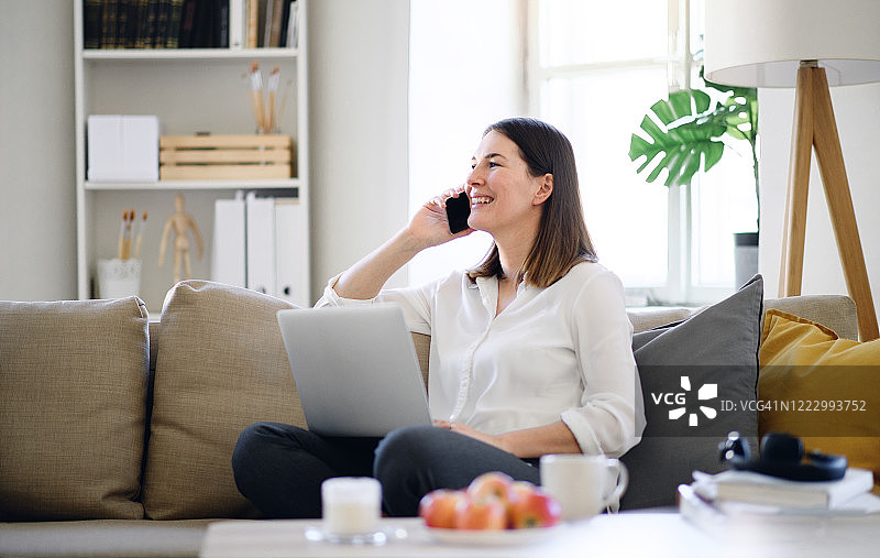 年轻女人在家用笔记本电脑和智能手机工作，隔离概念图片素材