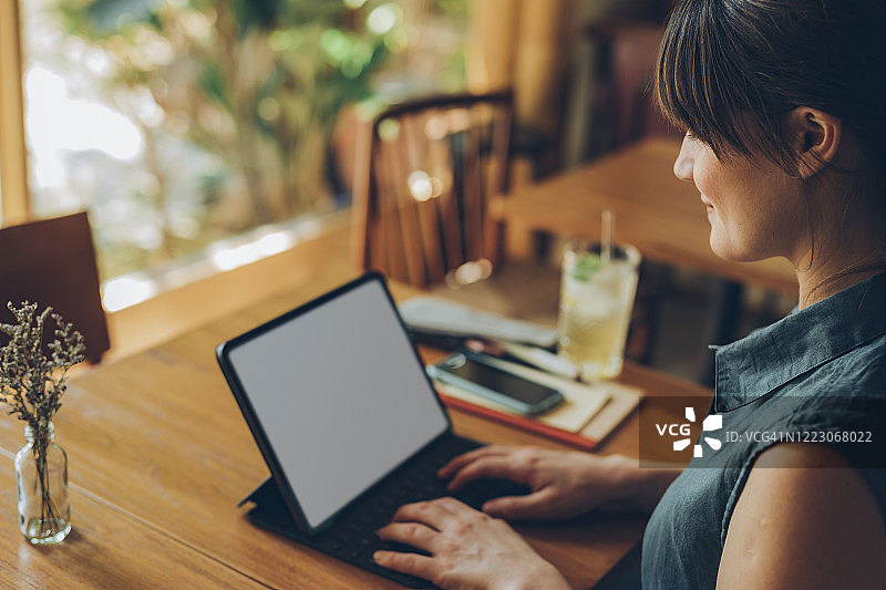 快乐的年轻自由职业者在当地咖啡馆使用她的数位平板电脑（空白屏幕，复制空间）图片素材