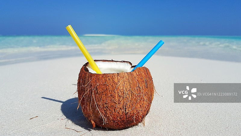 热带水果汁概念设计，留白区域，白色沙滩上的椰子汁，太平洋和多云天空背景图片素材