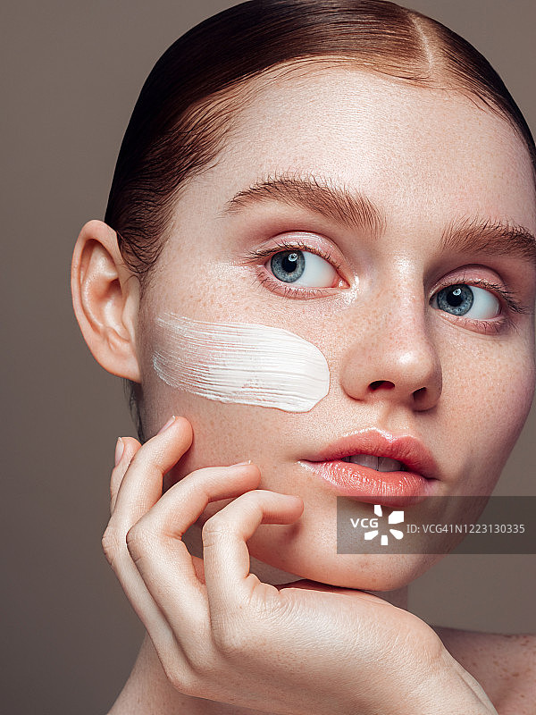 年轻女孩在脸上涂抹乳霜图片素材