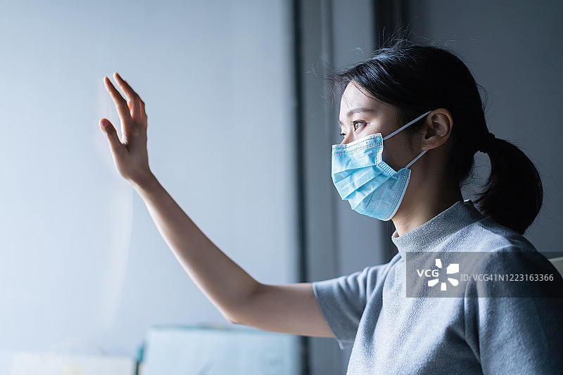 戴防护面罩隔窗观望的女人图片素材