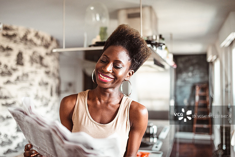 在厨房里看报纸的幸福女人图片素材