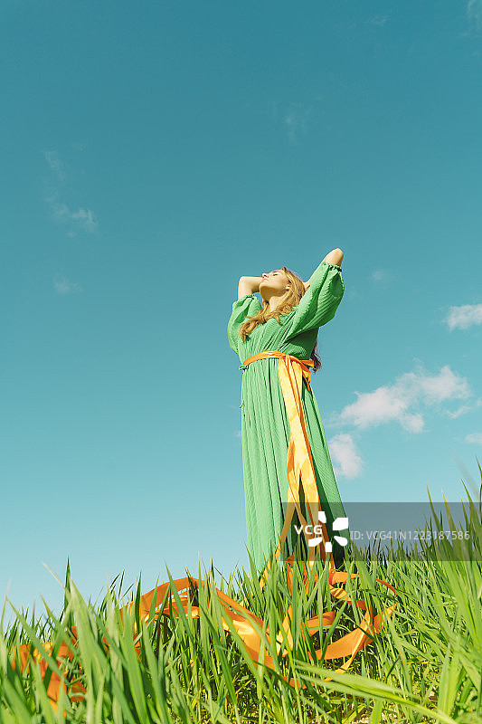 穿着绿色连衣裙，腰间系着彩带的年轻女人图片素材