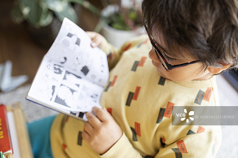 戴眼镜的小男孩在读漫画图片素材