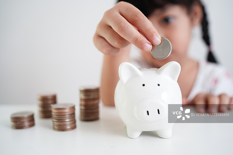 亚洲小女孩往存钱罐放硬币图片素材