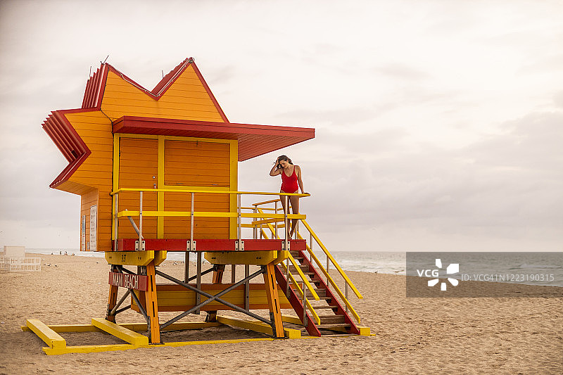 美国佛罗里达州迈阿密海滩救生员小屋上的红泳衣女子图片素材