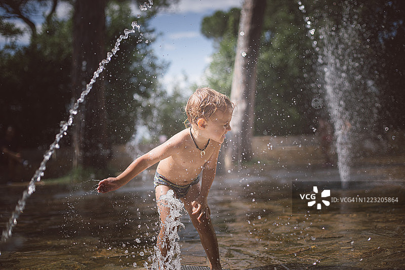 男孩在喷泉中玩耍图片素材