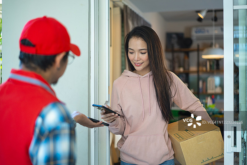 漂亮女人用手机扫描，从送货员那里取货图片素材