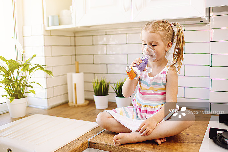 小女孩使用橙色哮喘吸入器图片素材