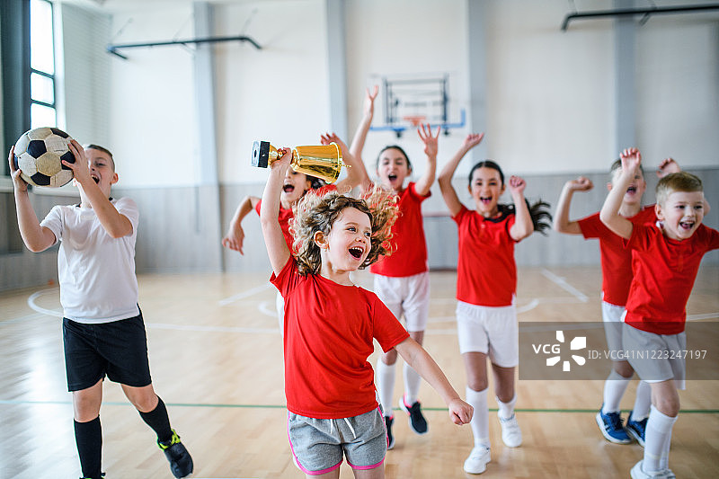 一群小孩在体育馆的课堂上用球和杯子欢呼的正面图图片素材