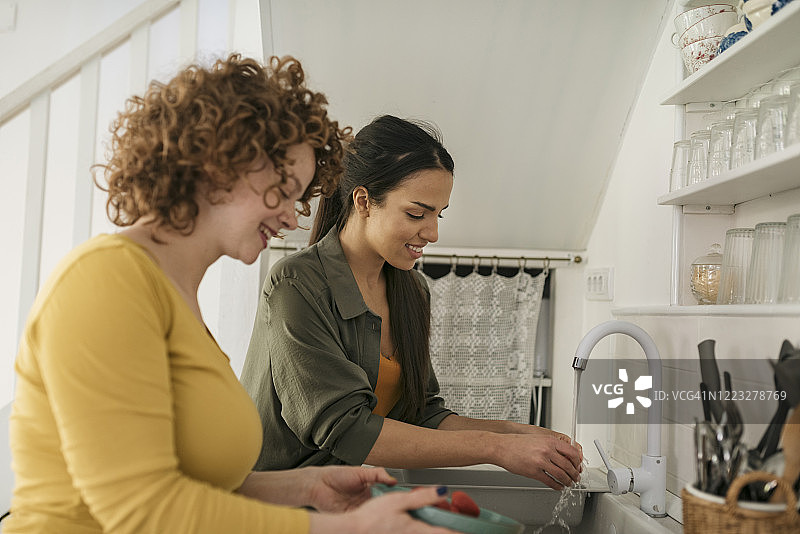 两位女性朋友清洗蔬菜的侧面视角图片素材