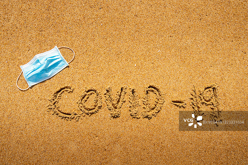 医用口罩落在沙滩上，新冠疫情概念。图片素材