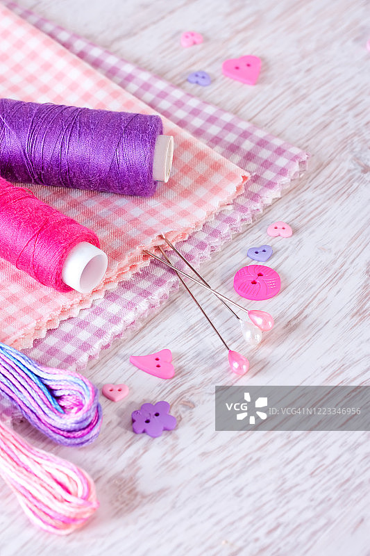 白色木桌背景上的缝纫工具：线、布料、纽扣、丝带图片素材