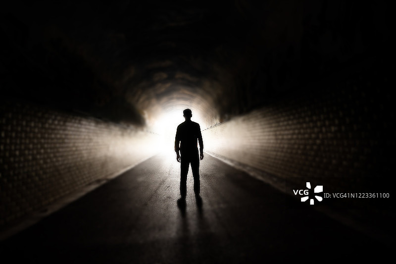 男人走在黑暗的隧道里图片素材