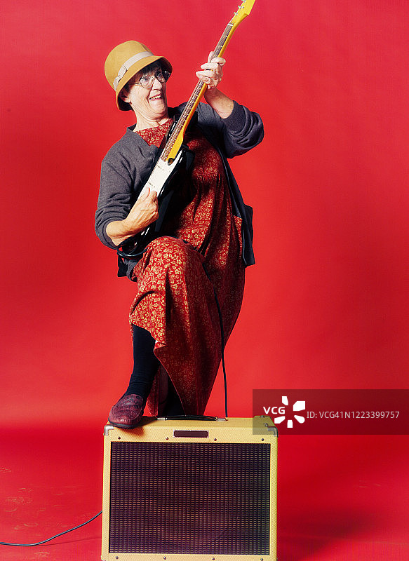 年长的女性，脚踩在放大器上，摇滚她的电吉他图片素材