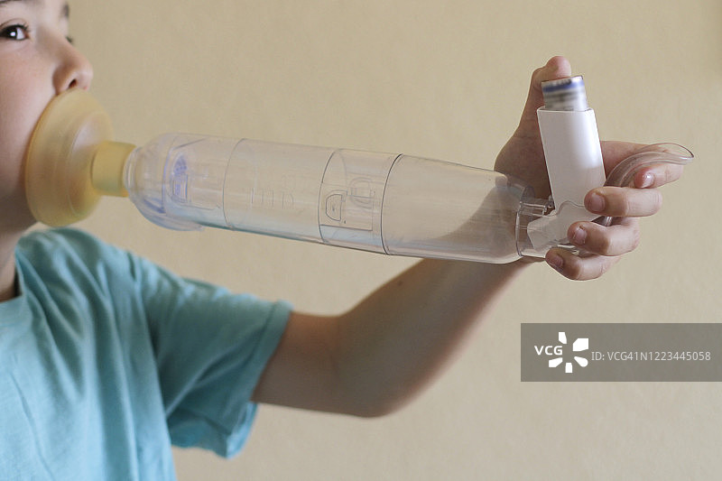 男孩使用哮喘吸入器的储雾罐图片素材