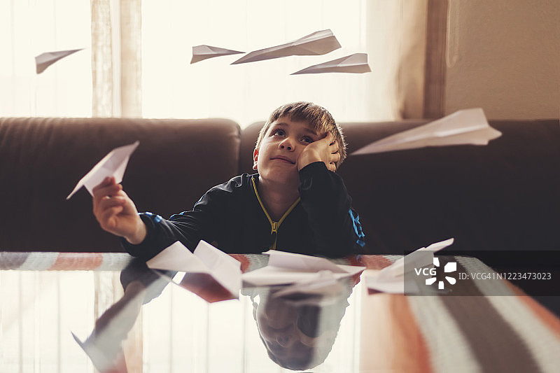 男孩在白日梦中，纸飞机在他周围飞舞。图片素材