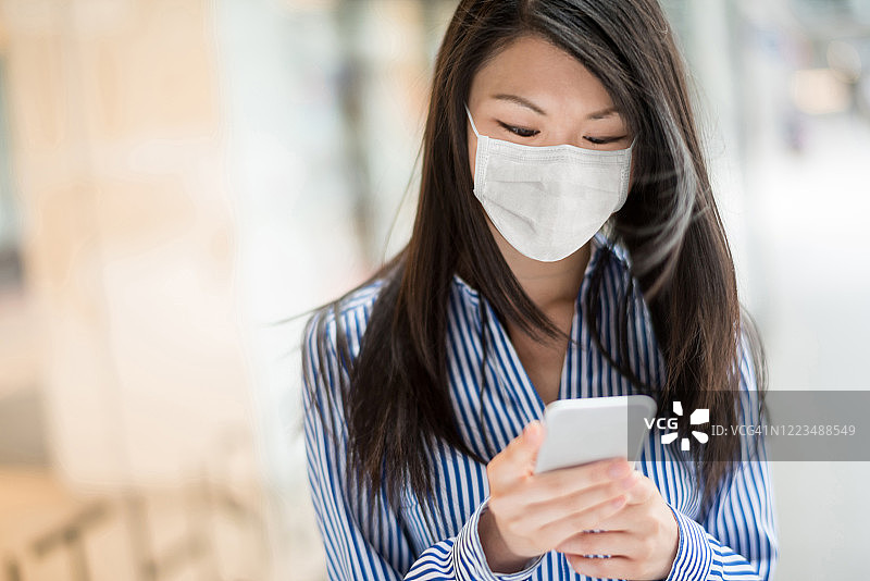 在办公室戴口罩发短信的亚洲女商人图片素材