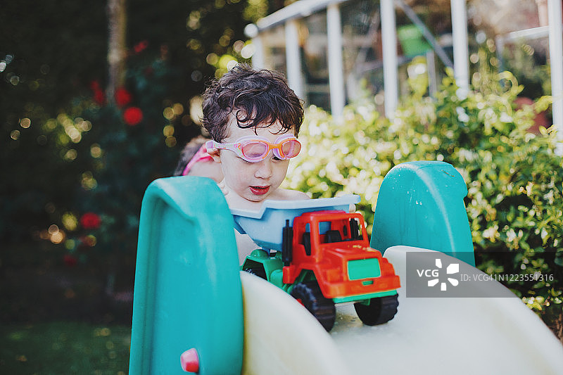 男孩在后院玩玩具卡车图片素材