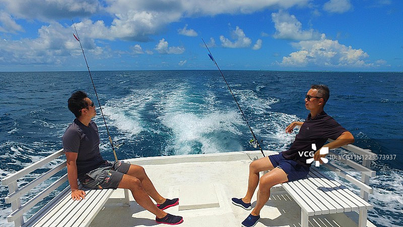 两位亚洲男游客在渔船上钓鱼，在假期中前往深海图片素材