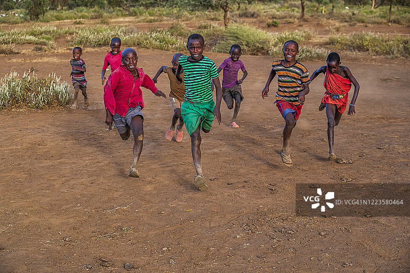 在乞力马扎罗山附近村庄的稀树草原上互相追逐的非洲儿童图片素材