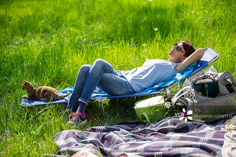 中年妇女与猫在草地上放松——库存照片图片素材