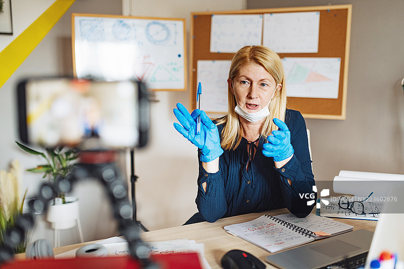 在隔离期间为学生上网课时戴着口罩和防护手套的教授图片素材