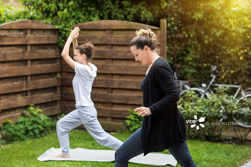 封锁期间，美丽的母亲和女儿在花园里锻炼图片素材
