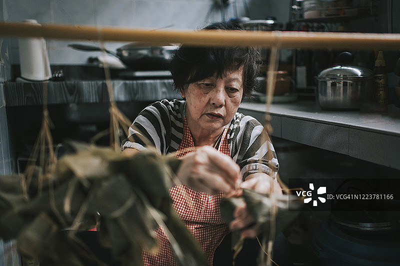 中国老年妇女在厨房准备粽子，为端午节做准备图片素材