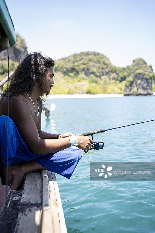 在泰国瑶亚岛乘船钓鱼的年轻男子图片素材