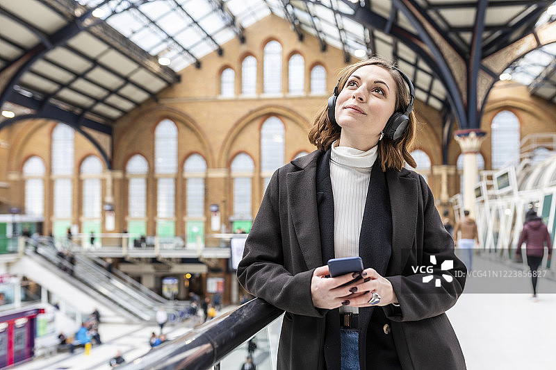 在英国伦敦火车站戴着耳机和手机的女人图片素材