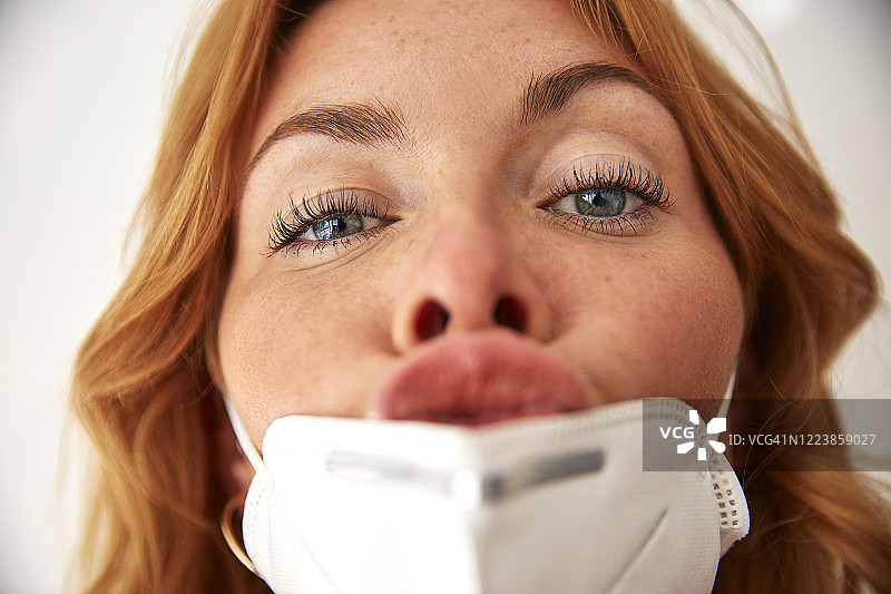 红发女子戴着口罩，嘴唇呈亲吻状人像图片素材