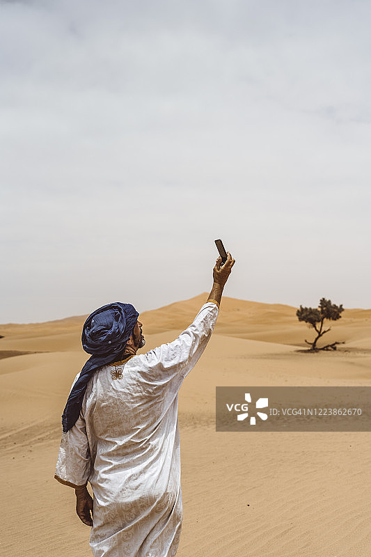 男子在沙漠里用智能手机自拍图片素材