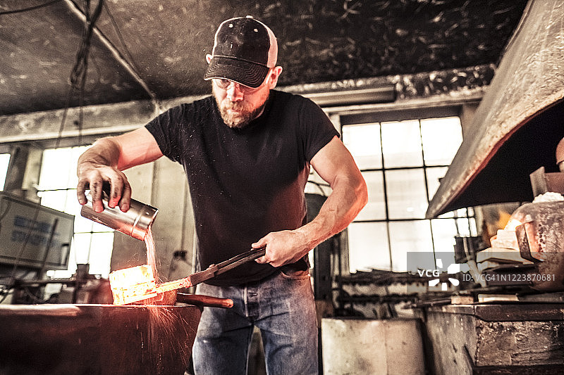刀匠在热大马士革钢上撒硼砂图片素材