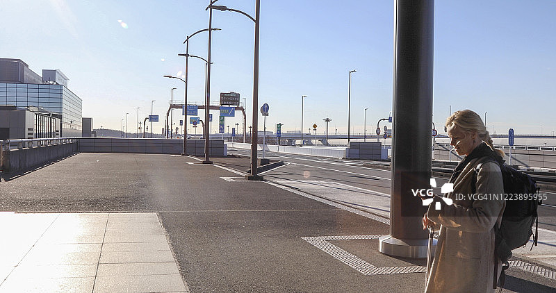 早上，中年妇女在空旷的机场外等候图片素材