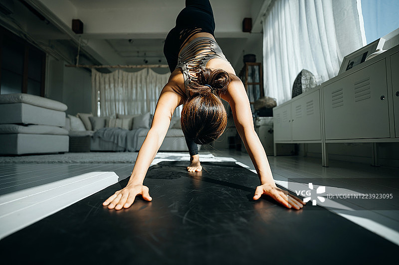 年轻的亚洲女性早晨在家中客厅练习瑜伽图片素材