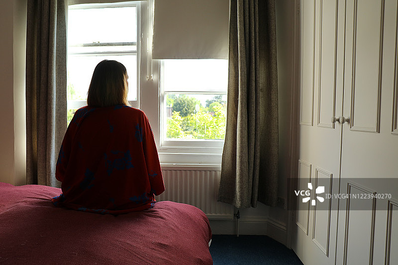 坐在床上望向窗外的孤独女人图片素材